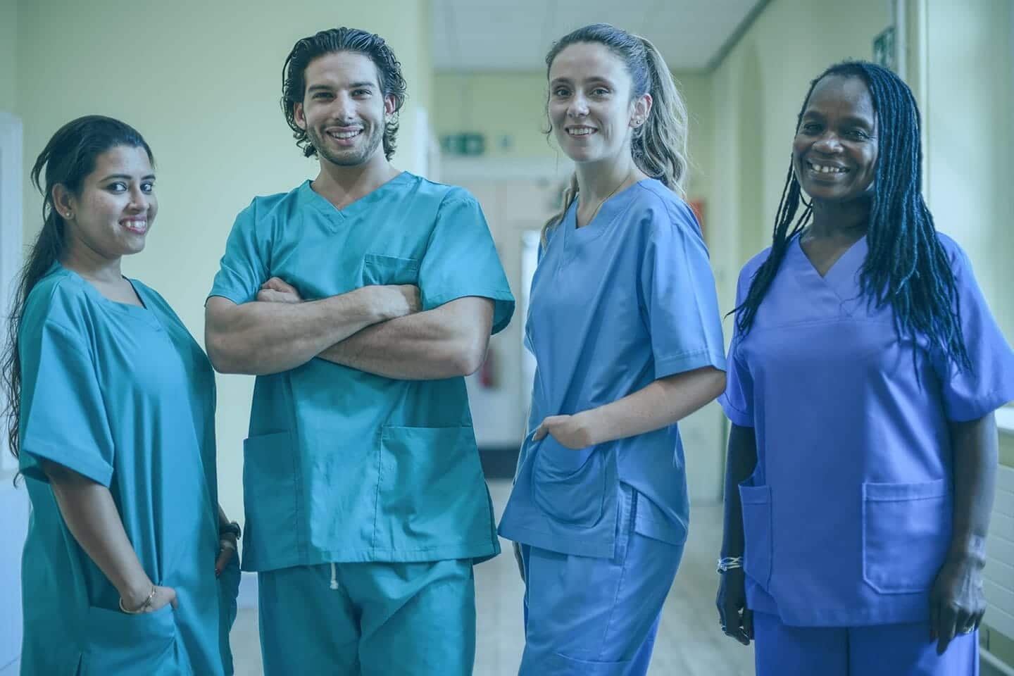 4 nurses in scrubs surrounded by nurse call systems