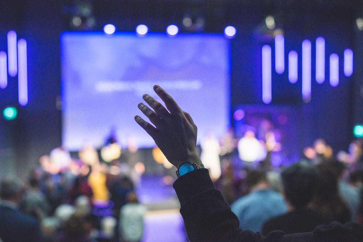 A hand raised in worship at a church event. Elevate church worship with professional sound systems from Marshall Industries.