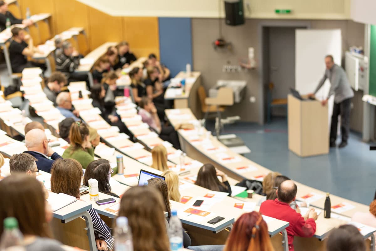 A college classroom full of students being lectured by a professor. A high-quality sound system helps educational institutions more effectively teach their students.