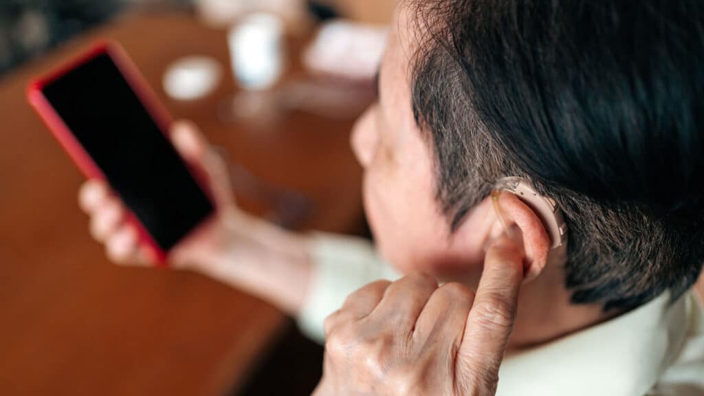 A man with a hearing aid and a smartphone in his hand, allowing him to easily hear and understand court proceedings