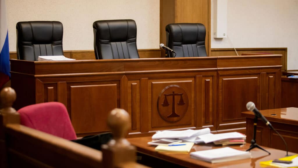 A courtroom with microphones, books and notes on desks, and other AV technology to help the court proceedings run smoothly