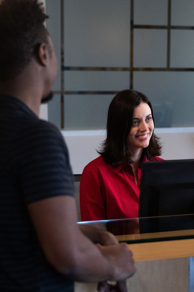 Front office staff greeting a visitor at the reception desk, the first-impression space Marshall Industries equips with intercom and video entry systems.