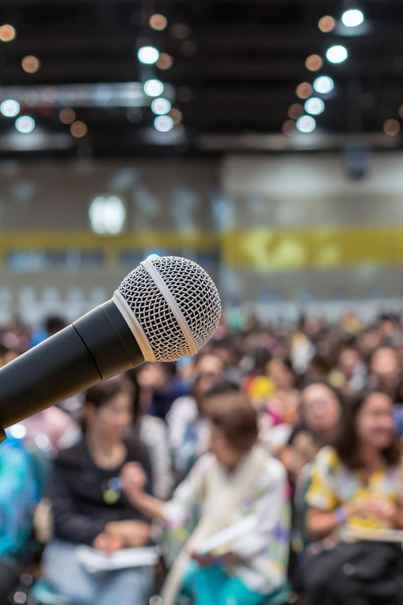 Wireless microphone in a packed school auditorium, the kind of live event Marshall Industries' AV systems are designed to support clearly.